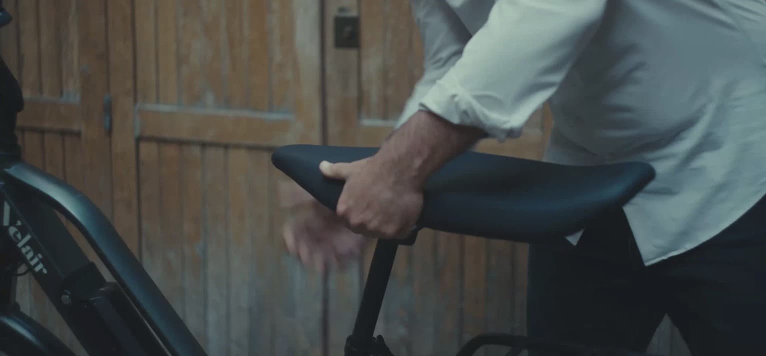 Hands fitting a Selle Jallot two-seater saddle onto a bike, in a workshop