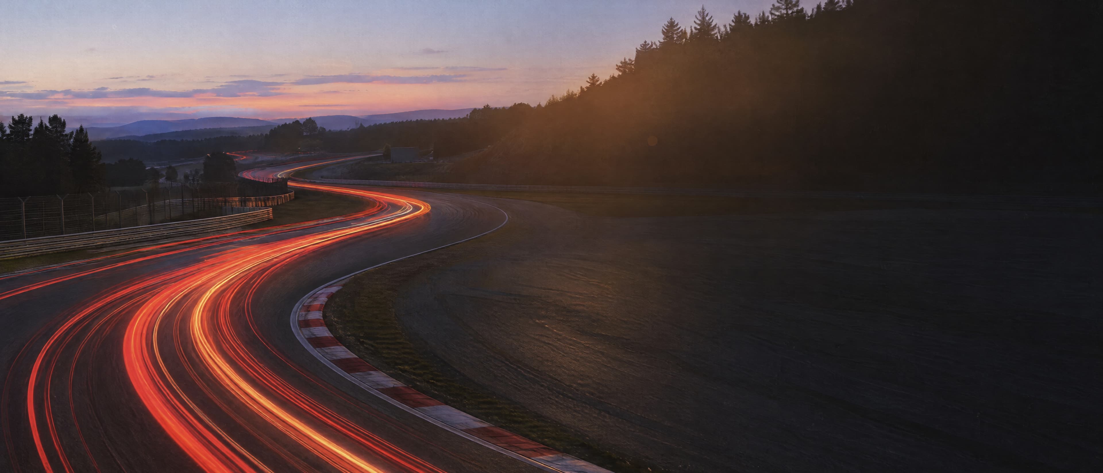 Racetrack at dusk, red light trails through a bend